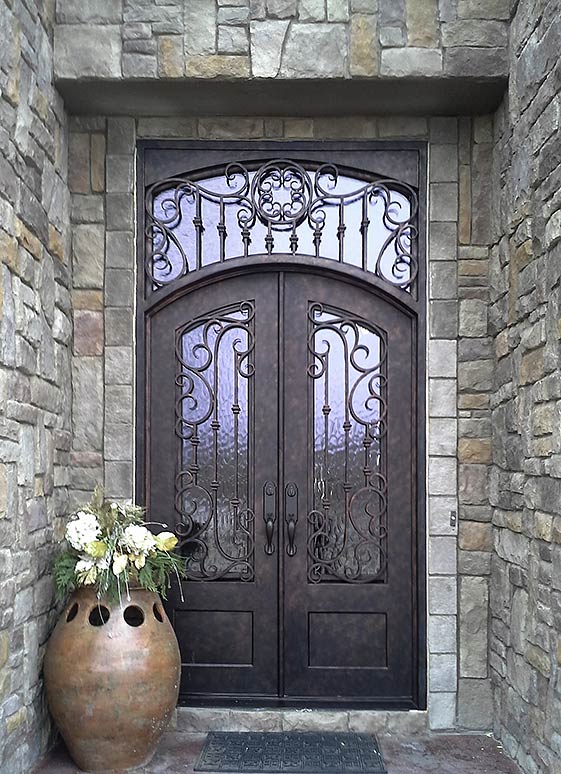 Custom Iron double door entry, Tuscan style, arched top, transom, Flemish glass, ¾” glass panels, operable iron grill, hand rubbed bronze finish, Patented Thermal Break