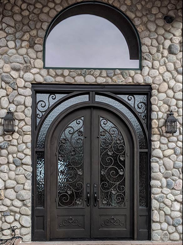 Custom round top double door iron entry with 10’ surround sidelight / transom, Flemish glass, French Country style, hand cast iron leaves, including scroll work on bottom panels, Patented Thermal Break, Hand Rubbed Bronze finish